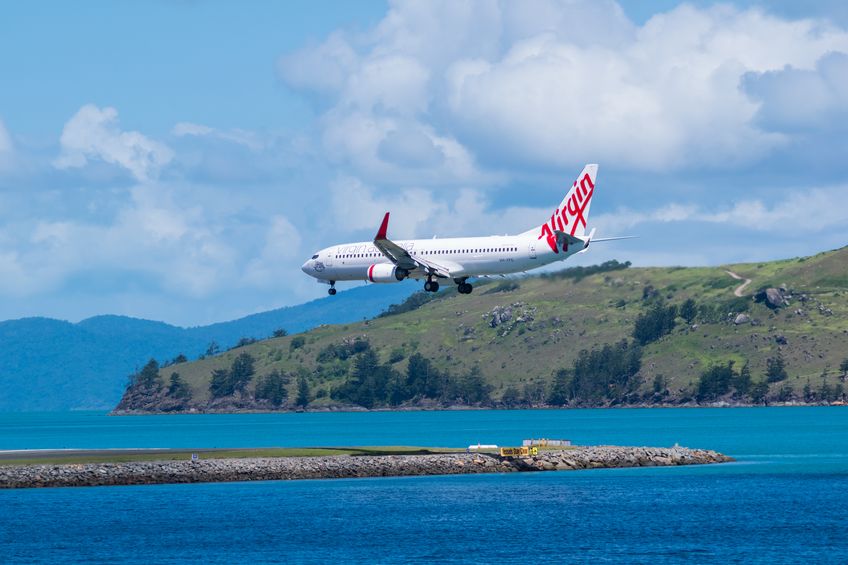 Hamilton island Australia, April 17-2014 Boeing 737-800 flying above the water is about to land on the runway on a beautiful day.